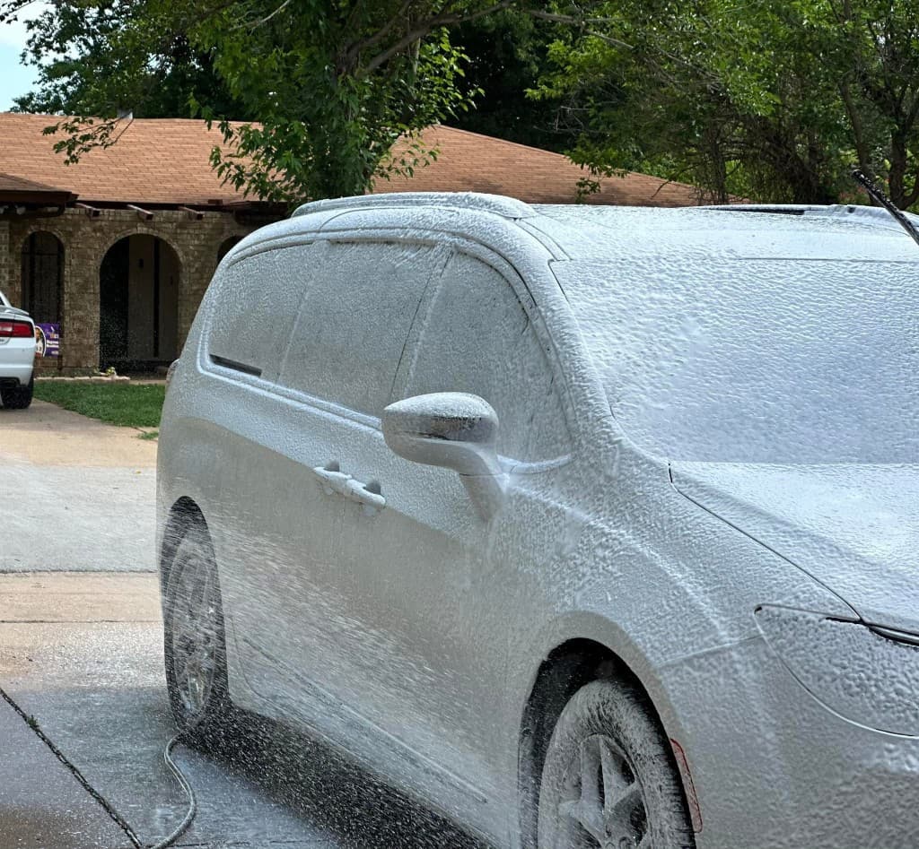 White minivan covered in thick foam during professional exterior auto detailing
