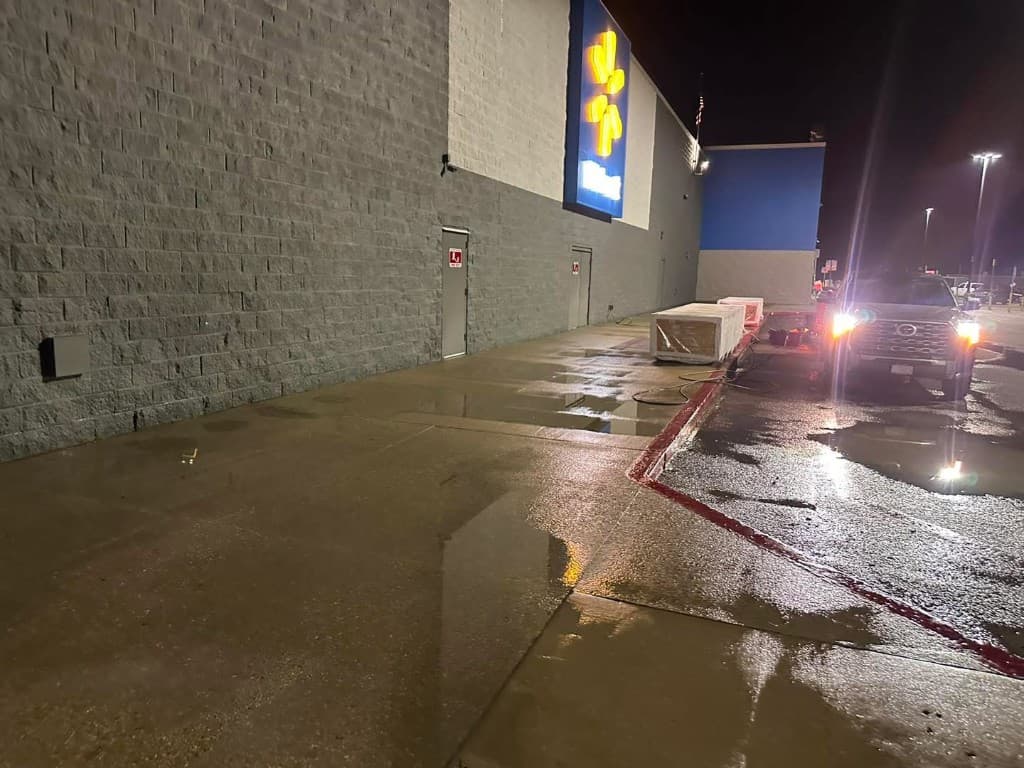 Commercial power washing at a Walmart storefront with wet pavement after cleaning