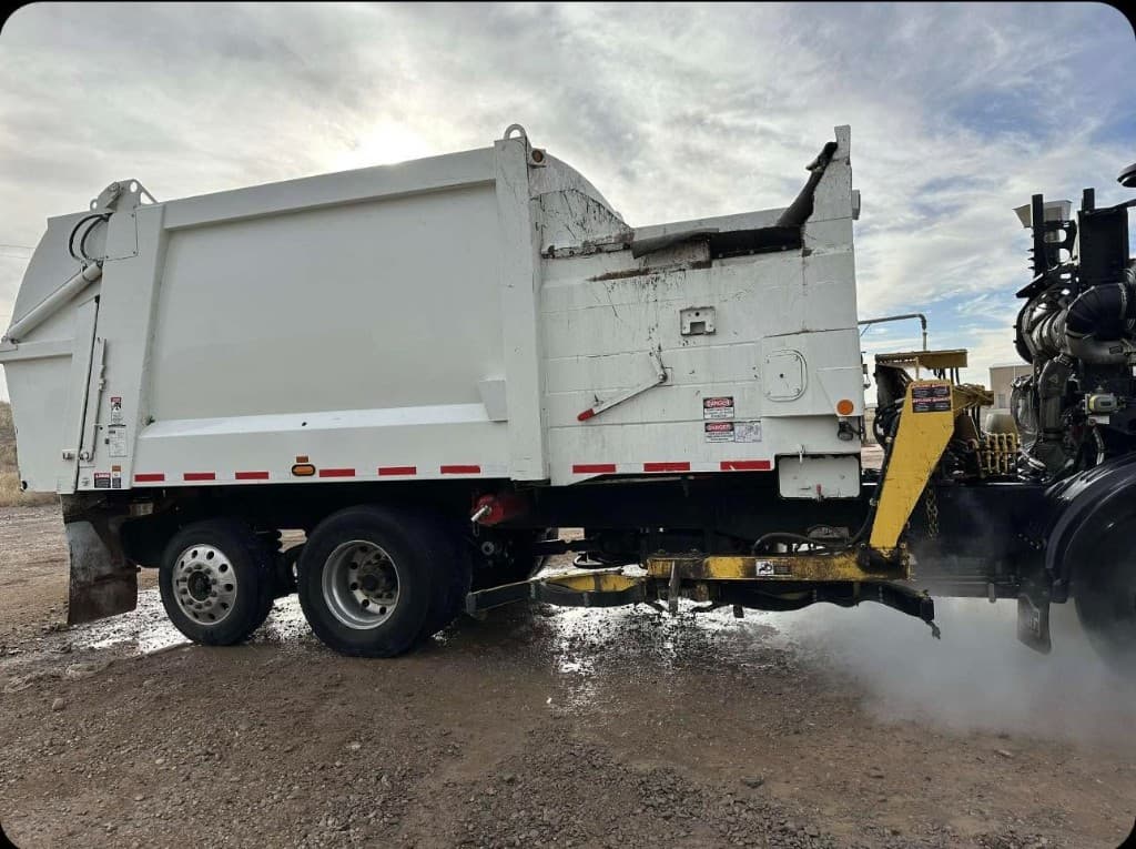 Heavy equipment being pressure washed with steam on a job site